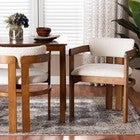 Two cream boucle dining chairs with wooden frames at a table