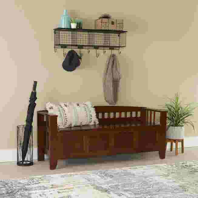 Wooden storage bench in a hallway with umbrella stand and plant