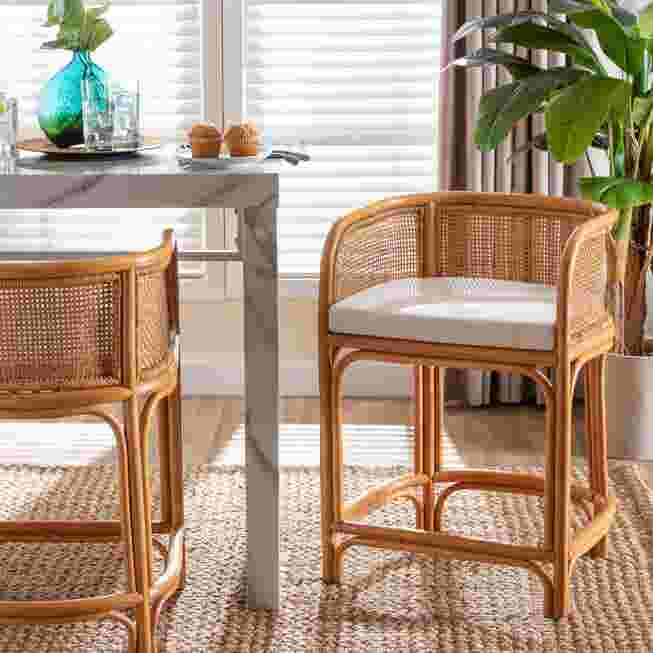 Natural rattan counter stool with white cushion in a modern kitchen setting