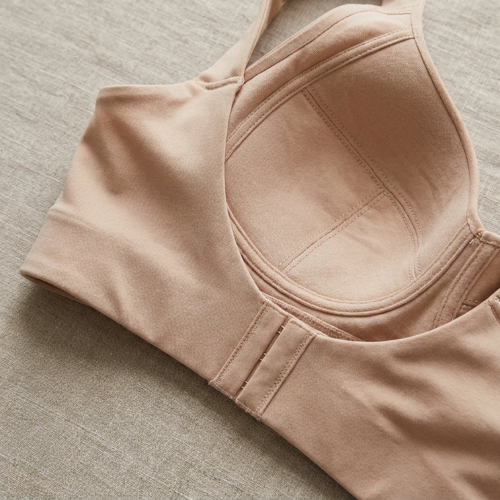 Close-up of a wireless bra's wide back panel and seamed cup construction against soft fabric.