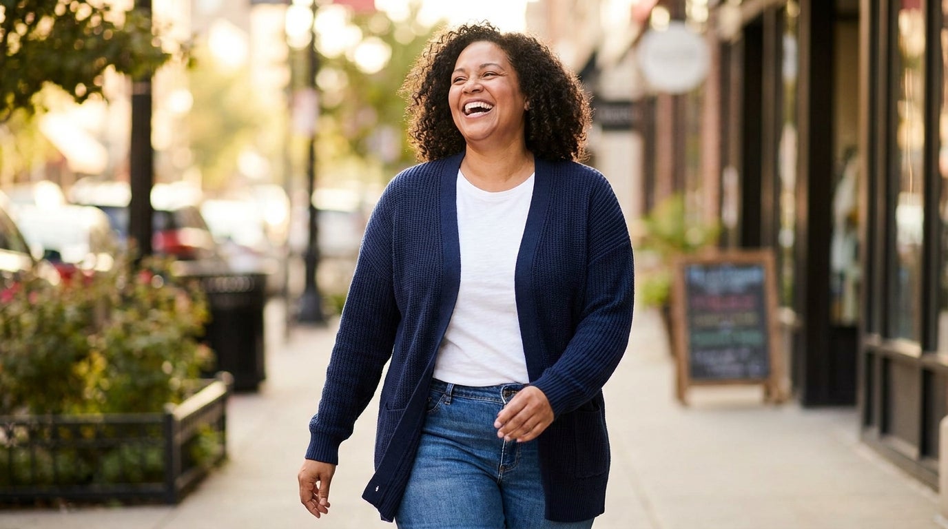 Woman layering an open-front cardigan with ribbed cuffs over a tunic outdoors